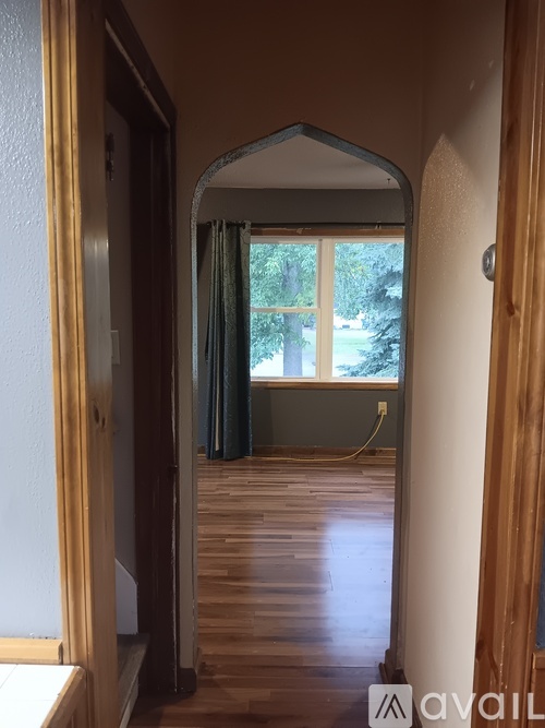 A room with wooden floors and a window with a view of trees.