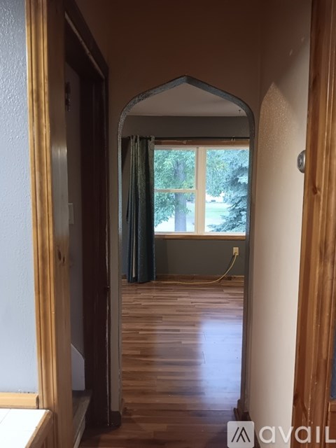 A room with wooden floors and a window with a view of trees.