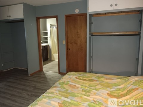 A bedroom with a bed, a wardrobe, and a shelf.