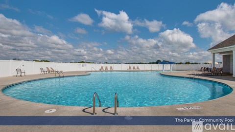 A community pool with a blue sky and clouds in the background.