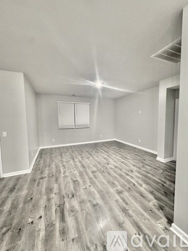 A spacious room with wooden flooring and white walls.