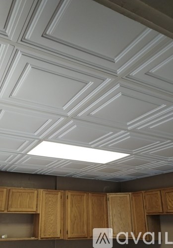 A kitchen with wooden cabinets and a ceiling with white panels.