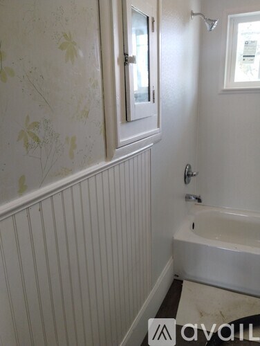 A bathroom with a white tub and a window.