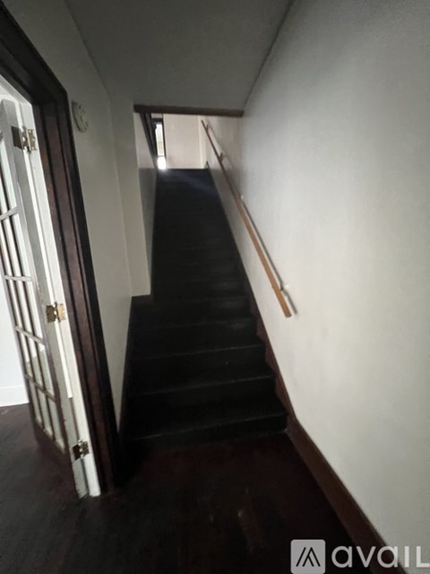 A staircase with a wooden handrail and a door at the top.