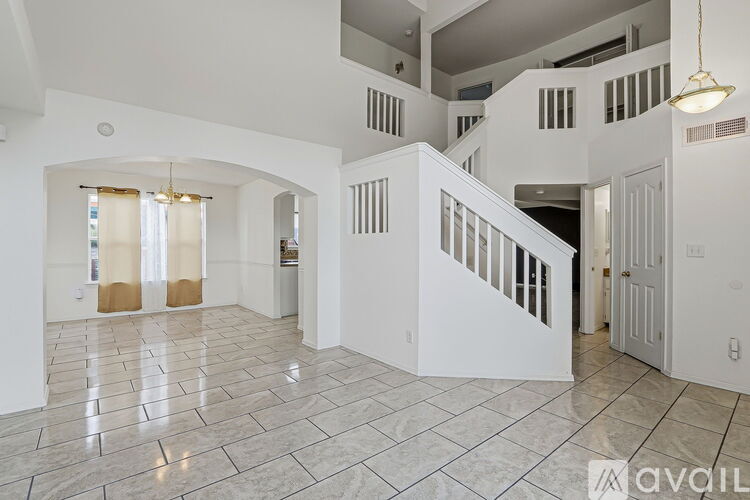 A spacious, white-walled interior with a marble floor and a staircase leading to another level.