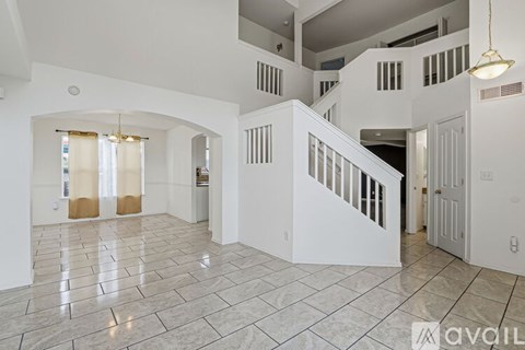 A spacious, white-walled interior with a marble floor and a staircase leading to another level.