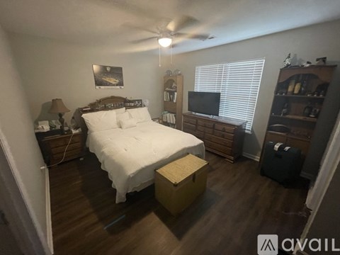 A bedroom with a bed, dresser, and a ceiling fan.