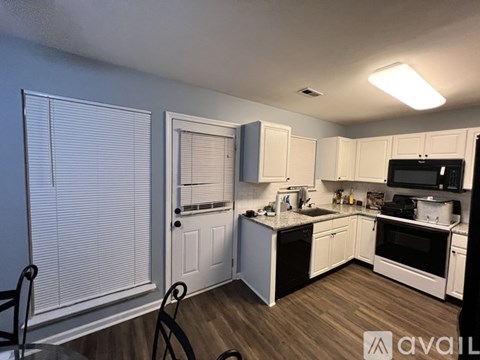 A kitchen with white cabinets and a black stove top oven.