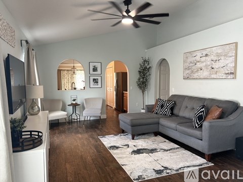A living room with a grey couch and a white chair.