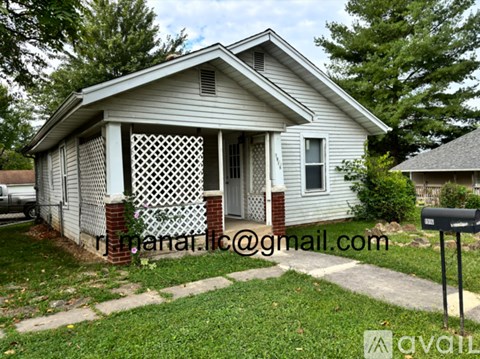 A small house with a porch and a mailbox in front.