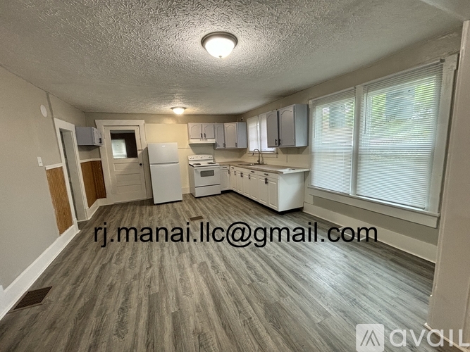 A kitchen with white appliances and wooden flooring.