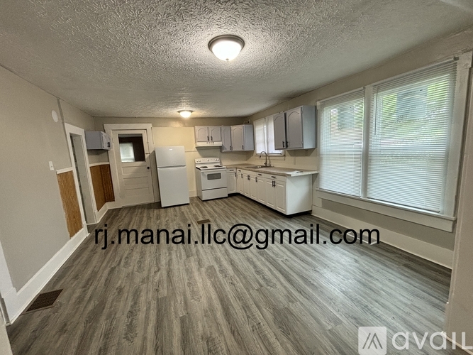A kitchen with white appliances and wooden flooring.