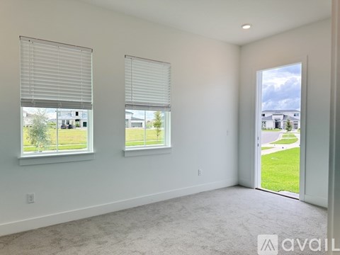A room with two windows and a door leading to a grassy area.