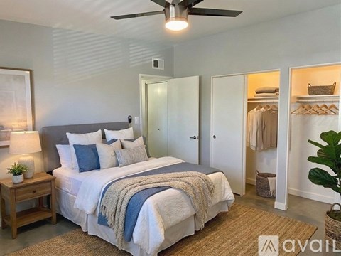 A bedroom with a bed, a ceiling fan, and a wardrobe.