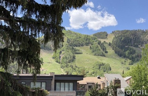 A house is situated in a valley with a mountainous background.