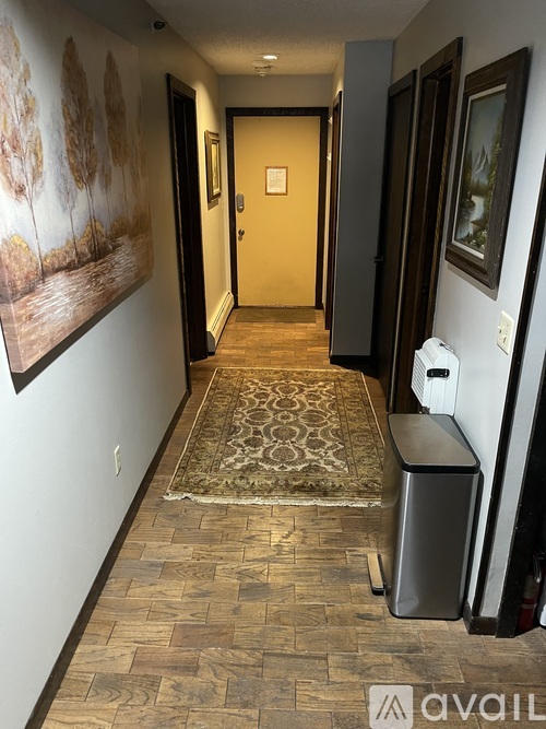 A hallway with a carpeted floor and a wall with a painting of trees.