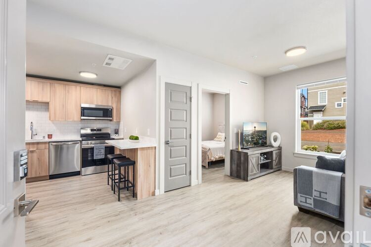 A modern kitchen with a dining area and a living room with a couch and a chair.