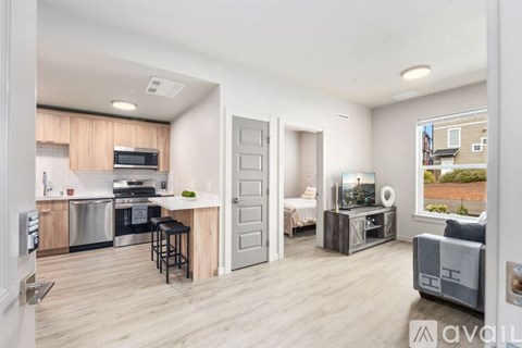 A modern kitchen with a dining area and a living room with a couch and a chair.