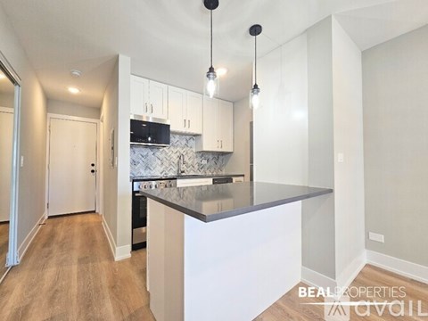 A modern kitchen with a large island and pendant lights.