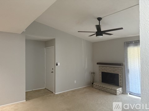 A living room with a fireplace and a ceiling fan.