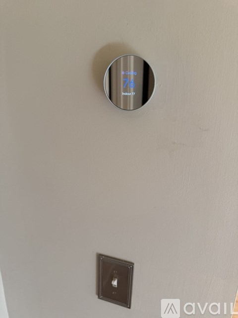 A round thermostat on a wall with the number 76 on it.
