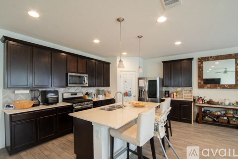 A kitchen with dark brown cabinets and a white island.
