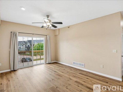 A spacious room with a ceiling fan and sliding glass doors leading to a balcony.