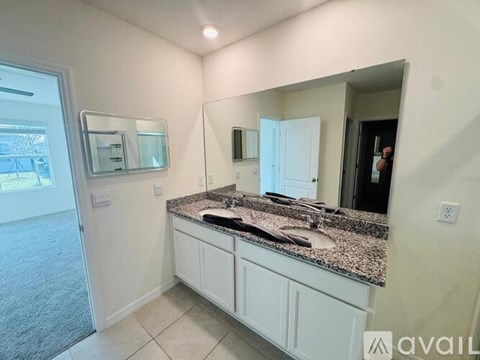 A bathroom with a granite countertop and white cabinets.