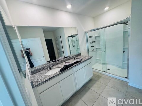 A bathroom with a sink, mirror, and shower.