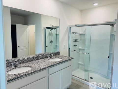 A bathroom with a glass shower door and a granite countertop.