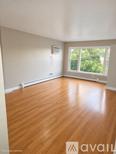 A room with wooden floors and a window overlooking trees.