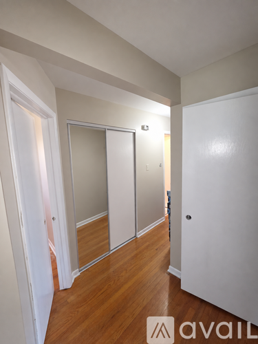 A hallway with a mirror on the wall and wooden floors.