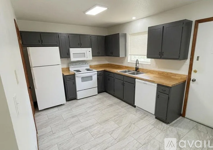 A kitchen with a white refrigerator, black cabinets, and a wooden countertop.