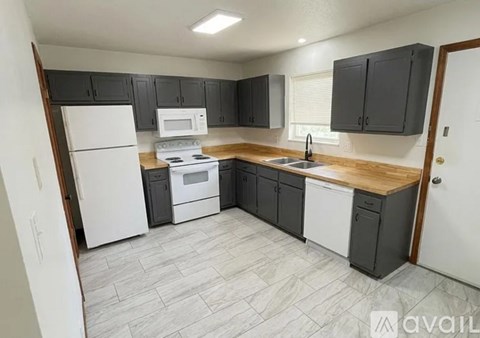 A kitchen with a white refrigerator, black cabinets, and a wooden countertop.