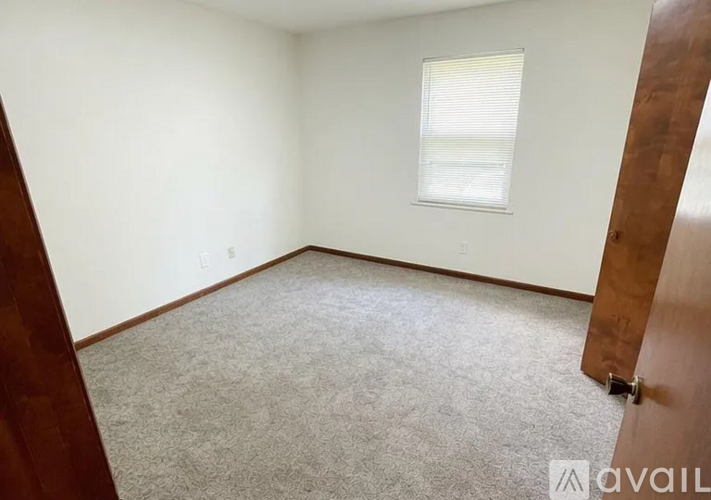 A room with a carpeted floor and a window with blinds.