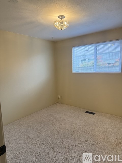 A room with a carpeted floor and a window showing a building outside.