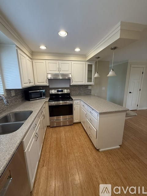 A kitchen with white cabinets and a wooden floor.