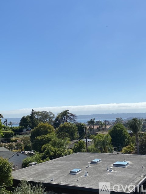 A rooftop with a clear blue sky and some trees in the background.