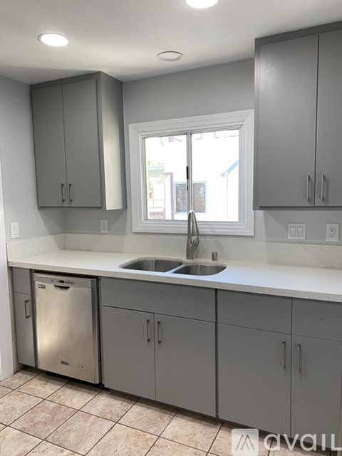 A kitchen with grey cabinets and a window.
