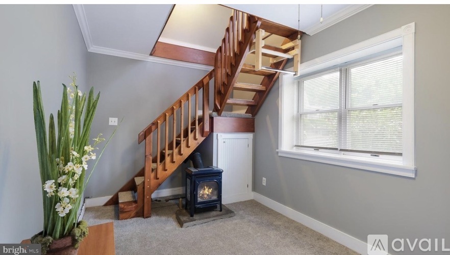 A living room with a staircase and a fireplace.