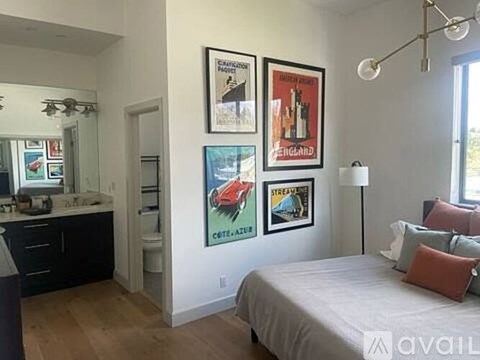 A bedroom with a bed, dresser, and a wall with framed pictures.