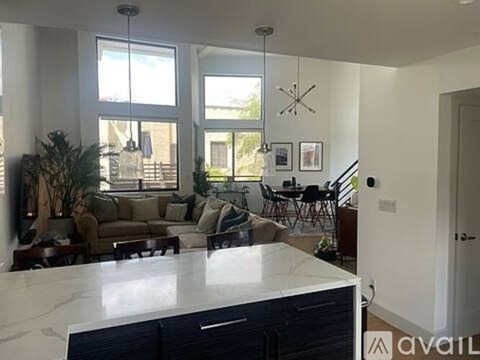 A kitchen with a marble countertop and a dining area with chairs and a table.
