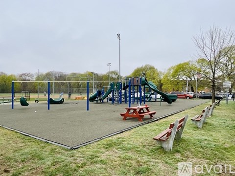 A playground with a green slide and red picnic tables.