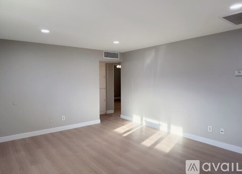 A spacious room with wooden flooring and a door on the right side.
