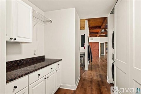 A kitchen with white cabinets and a black counter top.