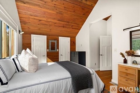 A bedroom with a large bed and wooden ceiling.