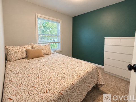 A bedroom with a bed, pillows, and a window.