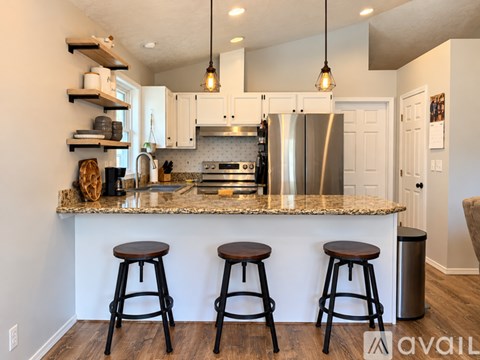 A kitchen with a granite countertop and bar stools.