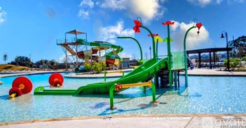 A green slide in a pool with red flower decorations.