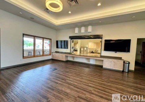A spacious living room with wood flooring and a television.